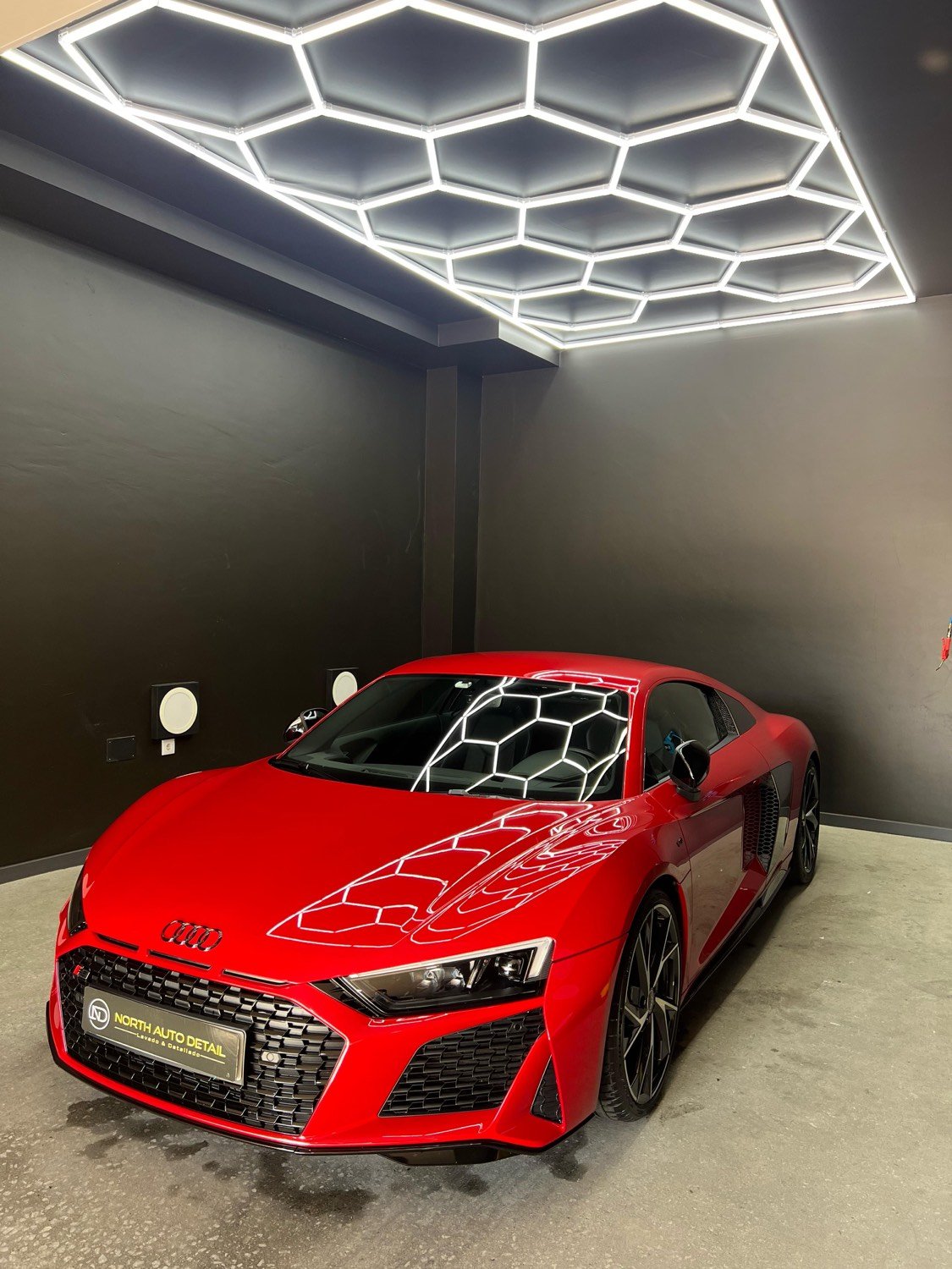Audi R8 rojo con la pintura corregida reflejando las luces